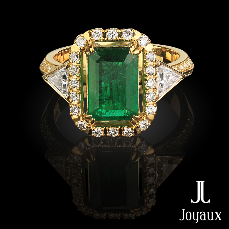 Gorgeous emerald ring in 18K yellow gold set with 64 brilliant-cut diamonds  (approx. 0.58 cttw.), two trillion-cut diamonds (approx. 0.32 cttw.) and